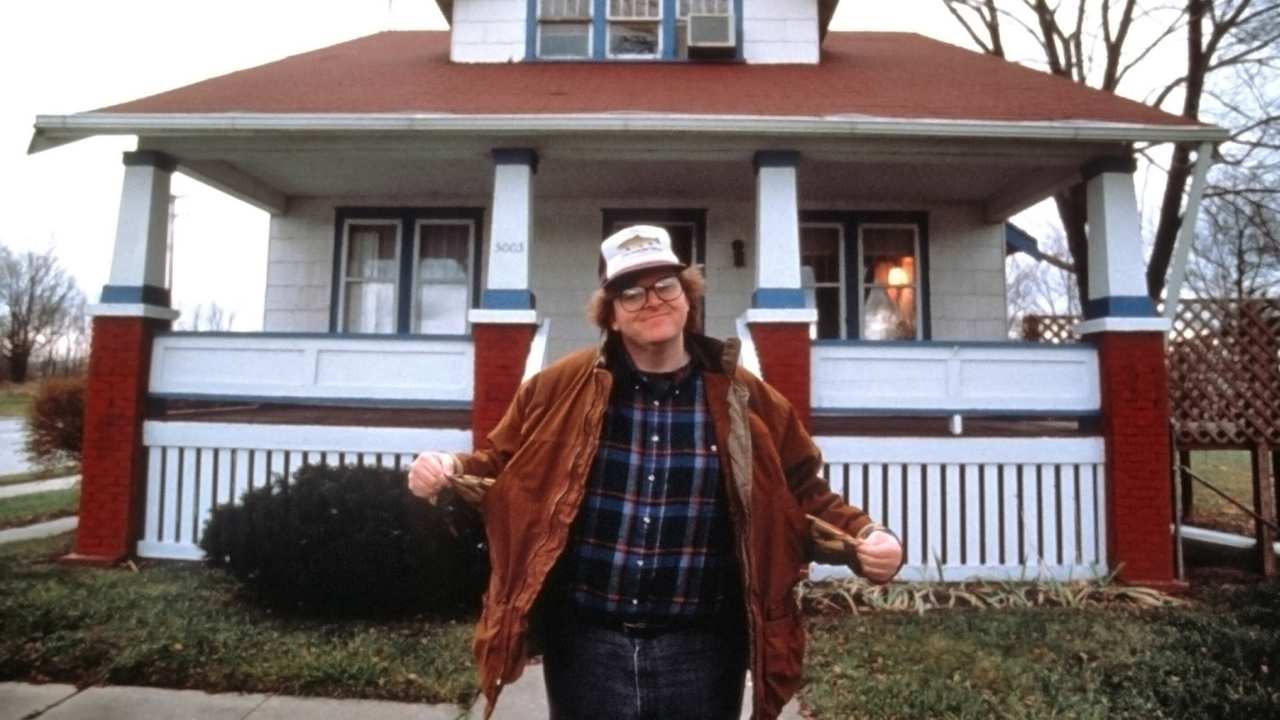 a man with glasses in front of a house
